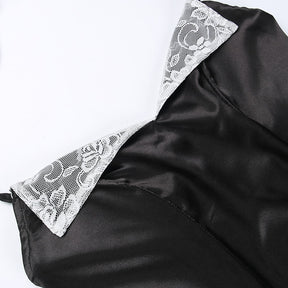 Close diagonal view of the black dress neckline, with both white floral lace lapels and fitted bodice seams visible.