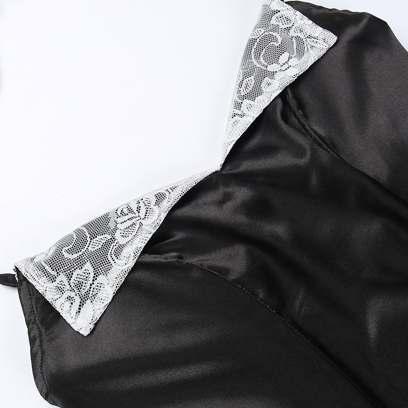 Close diagonal view of the black dress neckline, with both white floral lace lapels and fitted bodice seams visible.