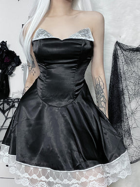 Black halter mini dress modeled from the front with one hand near the hair, showing the curved waist seam and scalloped white hem.
