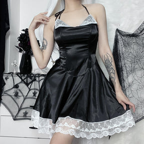 Model wearing the black satin-finish dress with white lace, holding the right side of the flared skirt while touching long white hair.