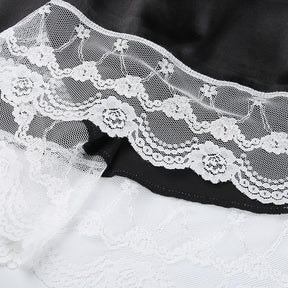 Close-up of the dress's white floral lace border, showing layered scallops and fine mesh along the black skirt.