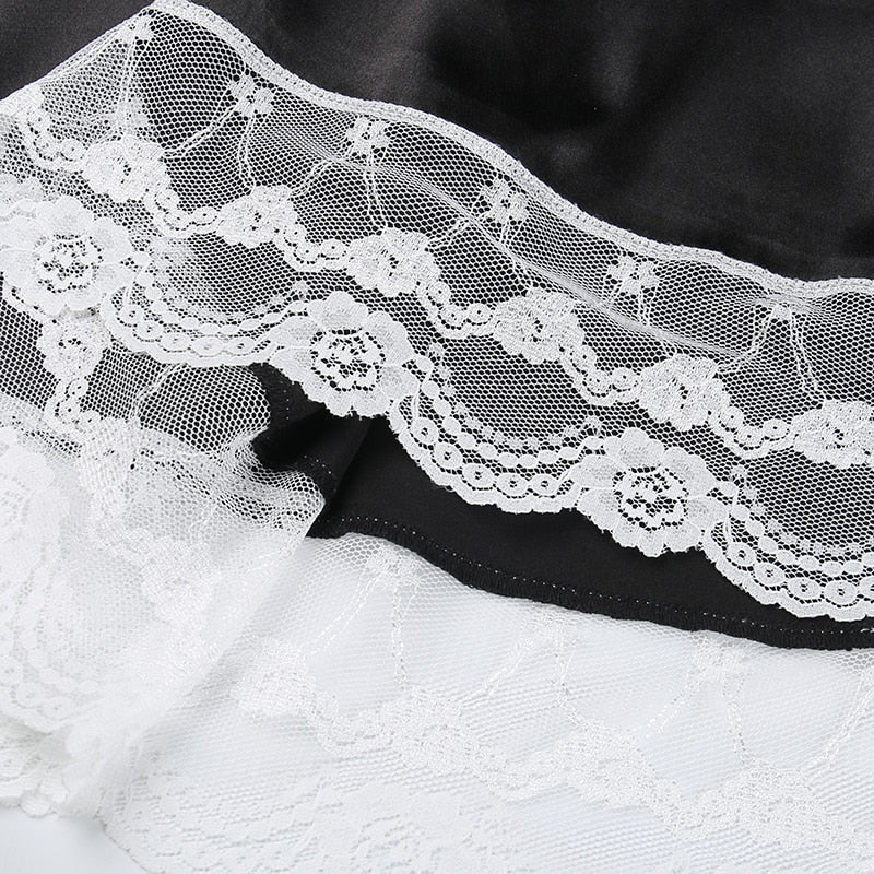 Close-up of the dress's white floral lace border, showing layered scallops and fine mesh along the black skirt.