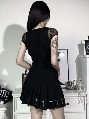 Rear view of the plain opaque black crop top with floral mesh cap sleeves, styled with a pleated cross-print skirt.