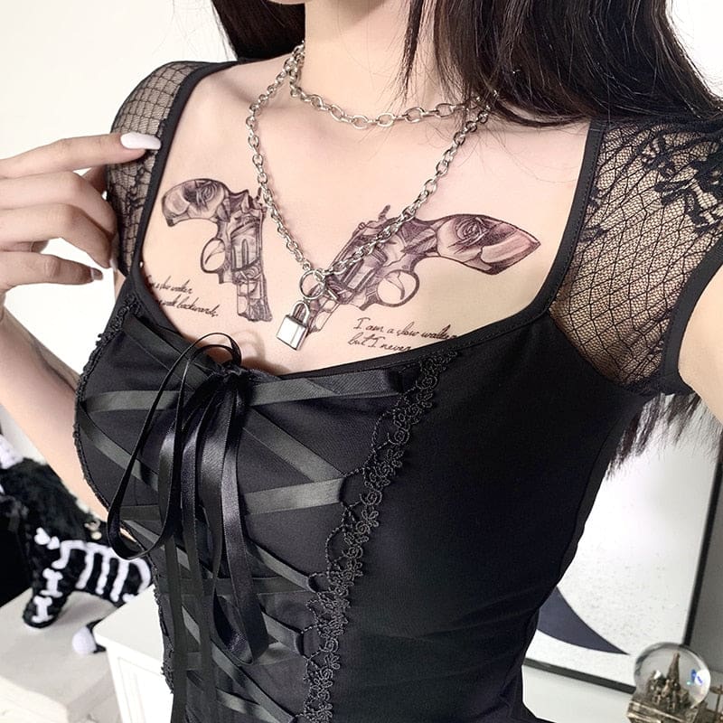 Angled close view of the black crop top, showing the sheer floral shoulder sleeve, broad neckline and ribbon lacing tied into a bow.