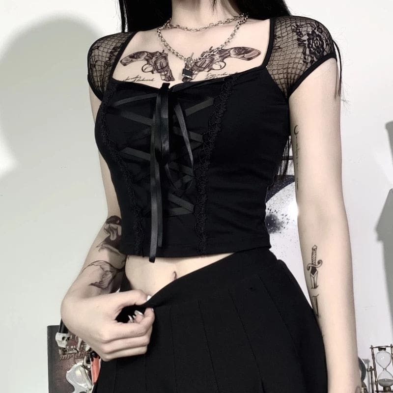 Front torso view of the black gothic crop top with ribbon lacing, sheer cap sleeves and a straight cropped hem above a dark skirt.
