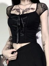 Black ribbon lace-up crop top worn with a dark skirt, showing sheer floral cap sleeves, a wide neckline and a satin-look bow at the top of the lacing.