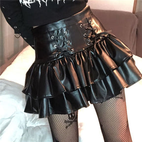 Another angled view of the black faux leather skirt under warm light, highlighting the paired lacing panels and folded ruffle edges.