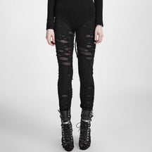 Straight-on front view of solid black ripped skinny pants, with fine mesh visible beneath the distressed openings and fitted legs ending above black ankle boots.