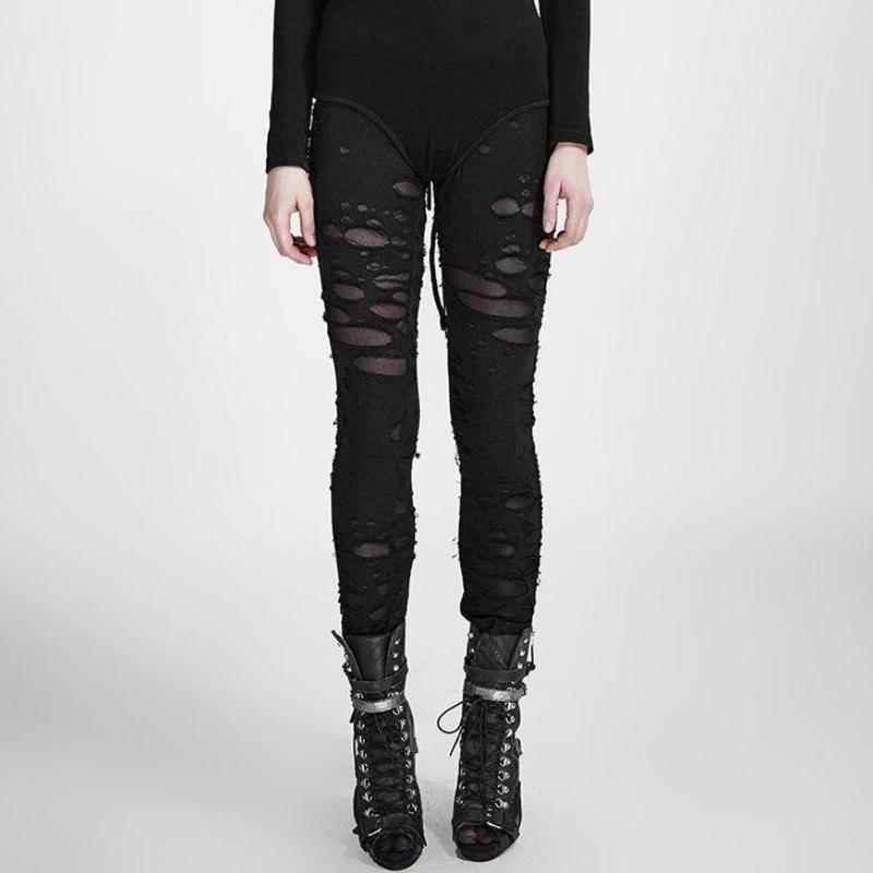 Straight-on front view of solid black ripped skinny pants, with fine mesh visible beneath the distressed openings and fitted legs ending above black ankle boots.