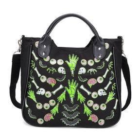 Black Monster Mash handbag with rounded top handles and a symmetrical print of green hands, eyeballs, pink brains, bones and bats across the front.