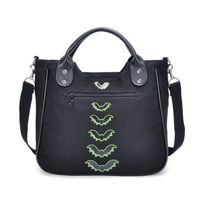 Back of the black Monster Mash handbag, showing a horizontal exterior zip pocket, a vertical row of green bats and rounded top handles.