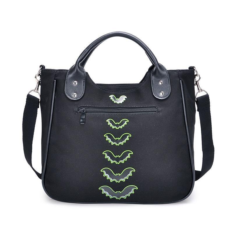 Back of the black Monster Mash handbag, showing a horizontal exterior zip pocket, a vertical row of green bats and rounded top handles.