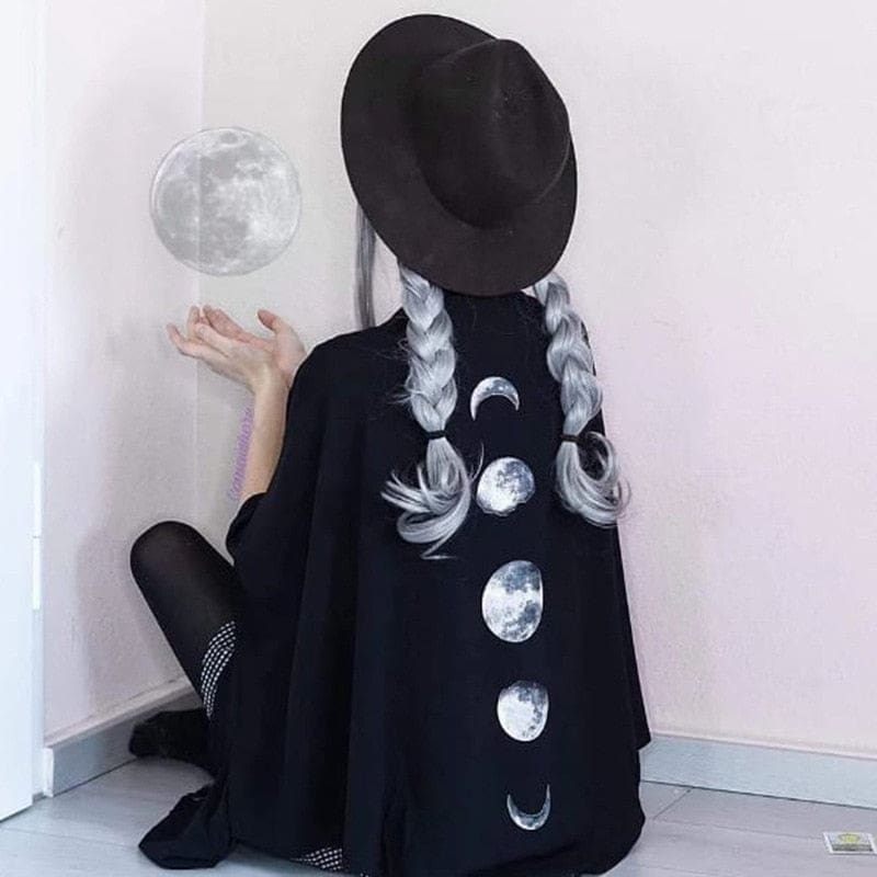 Seated styling of the black lunar wrap with a wide-brim hat, braids and the moon print facing outward.