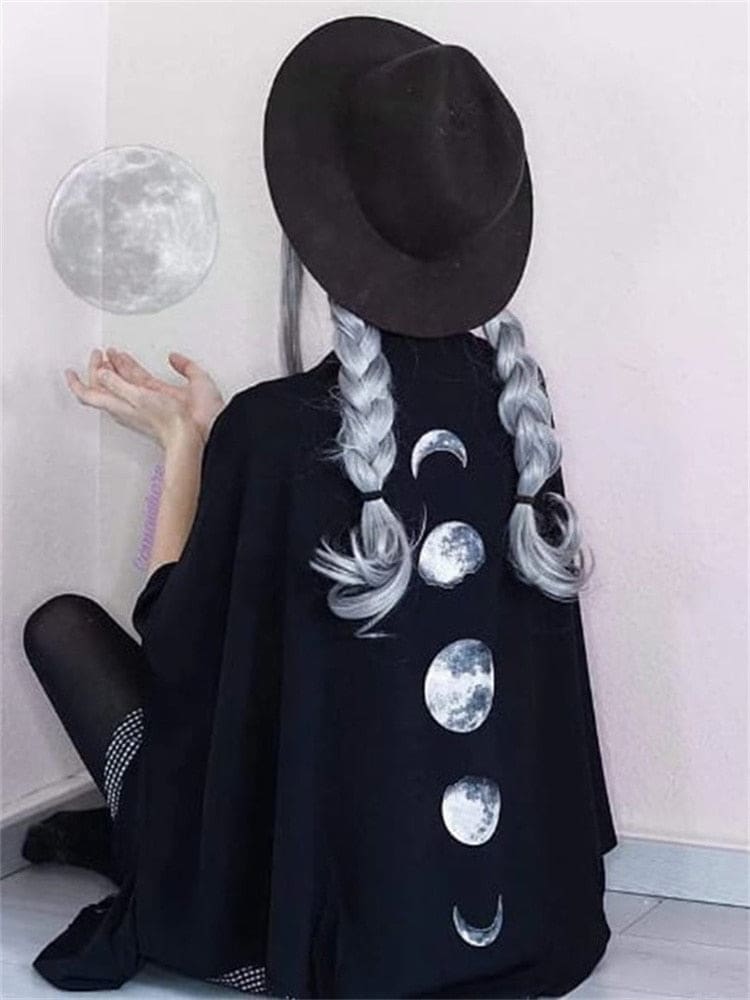 Five-moon print down the back of a black wrap styled with a wide-brim hat and pale braids.