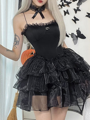 Angled front view of the black moon-charm mini dress, with one hand raised beside the thin strap.