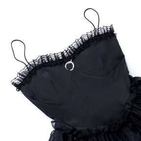 Black dress bodice laid flat, showing curved seams, lace trim and the small crescent detail.