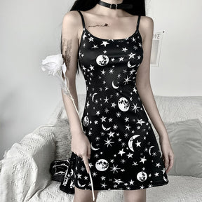 Black moon and star print mini dress shown from the front beside a white flower prop.