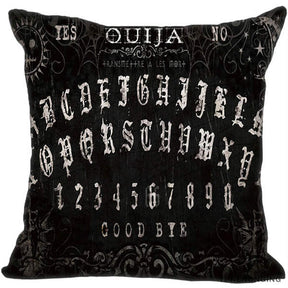 Black square Ouija pillow cover with decorative pale Gothic-style alphabet rows, fine curls and stars, and Yes, No and Good Bye lettering.