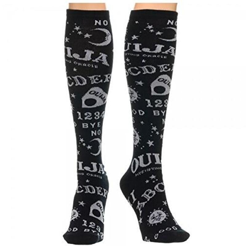 Black knee-high Ouija socks worn on crossed legs, showing white spirit-board lettering and celestial motifs around the calves.
