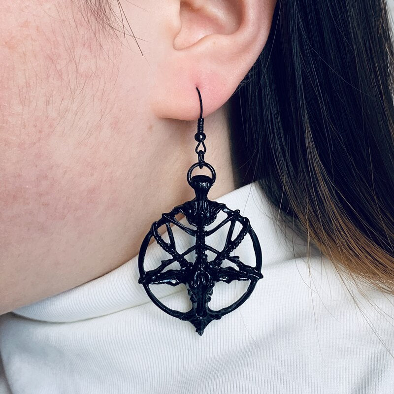 Black circular pentagram earring shown against a white shirt, with the horned-goat design hanging below the earlobe.