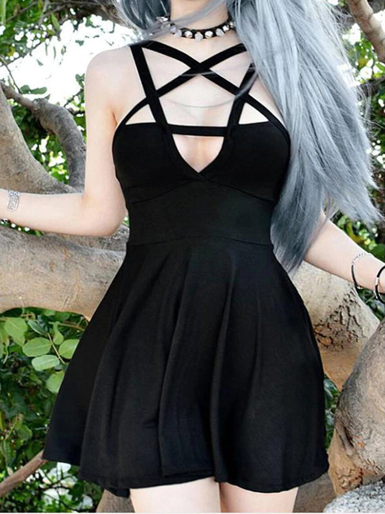 Front view of the black sleeveless dress beside a stone wall and green branches, clearly showing the five-point star straps and flared skirt.