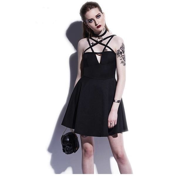 Studio view of the black pentagram strap dress against a pale wall, styled with a separate choker and small skull-shaped bag. The sleeveless bodice narrows at the waist above the flared skirt.