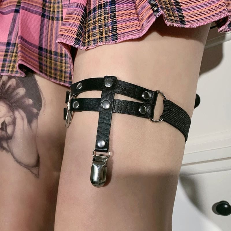 Side detail of the black garter on the thigh, showing the elastic back strap, rectangular adjuster and riveted connection to the front bands.