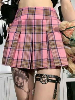 Pentagram thigh garter styled with a pink plaid skirt and dark stockings, showing the black parallel bands and hanging clips below the hem.