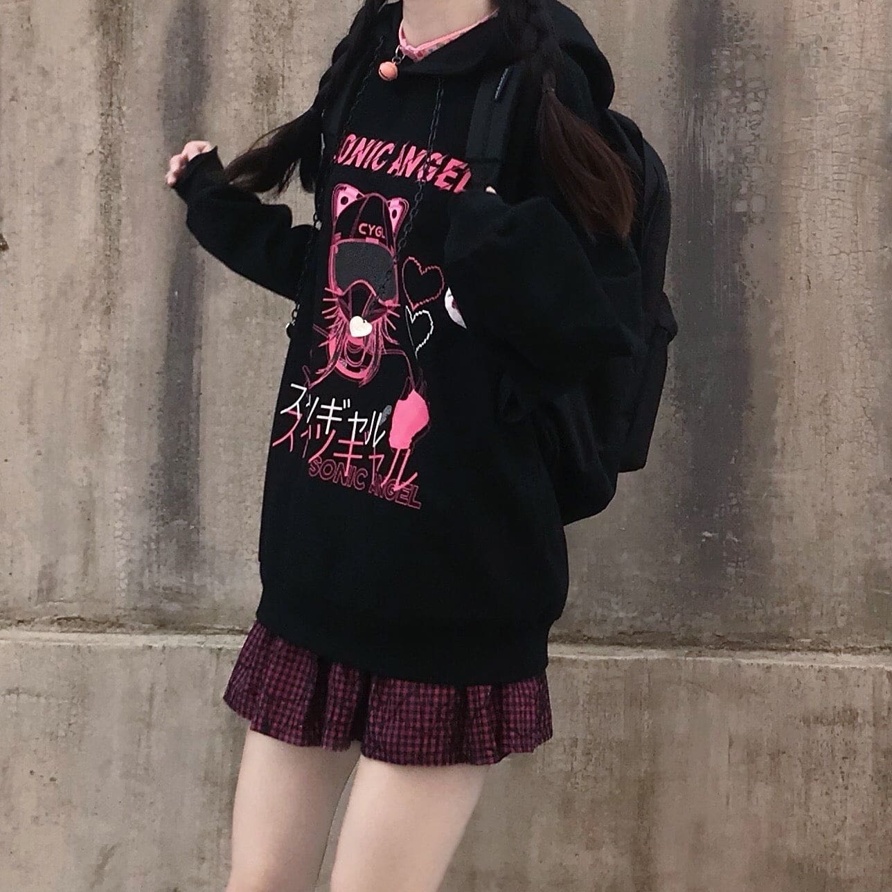 Standing front view of the black and pink hoodie, with long sleeves, dropped shoulders and braided hair.