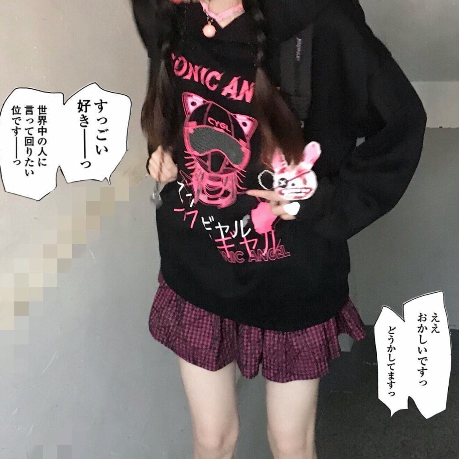 Front view of the black hoodie with pink graphic lettering and white hearts; comic-style text surrounds the model.
