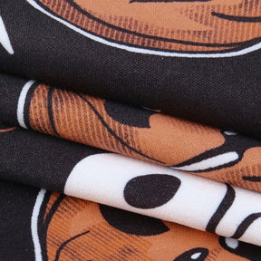 Macro view of the black dress fabric and Halloween artwork, highlighting orange pumpkin shapes and small white printed details.