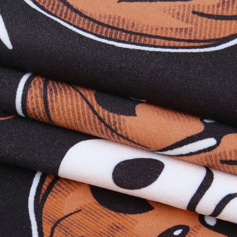 Macro view of the black dress fabric and Halloween artwork, highlighting orange pumpkin shapes and small white printed details.