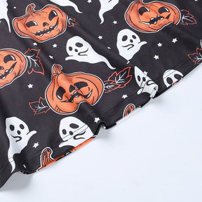 Detail of the black pumpkin-print dress hem, showing the stitched lower edge beneath orange jack-o-lanterns and white motifs.
