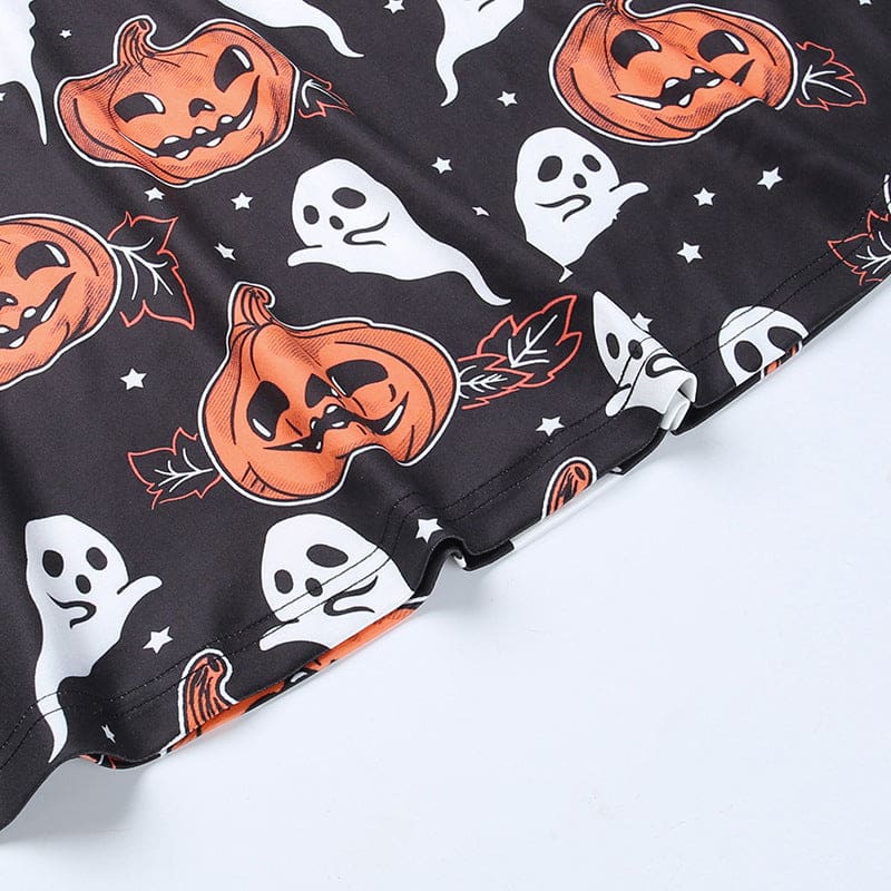 Detail of the black pumpkin-print dress hem, showing the stitched lower edge beneath orange jack-o-lanterns and white motifs.