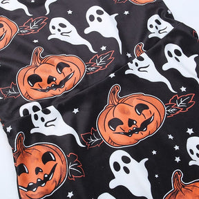 Close-up of the Halloween dress print, showing orange jack-o-lantern faces, curling stems, leaves, white ghosts and tiny stars on black.