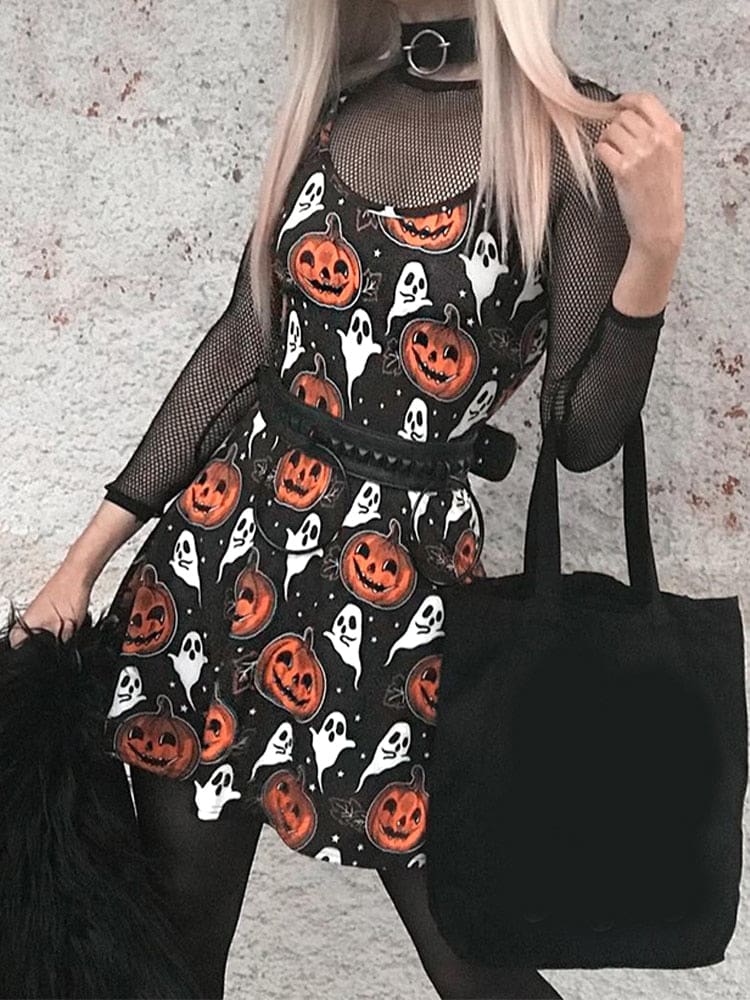 Front outfit view of the black pumpkin-print mini dress worn with a mesh underlayer, belt and black handbag outdoors.