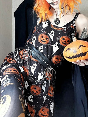 Orange-haired model seated near a wall in the black pumpkin-and-ghost mini dress, with a pumpkin beside the patterned skirt.