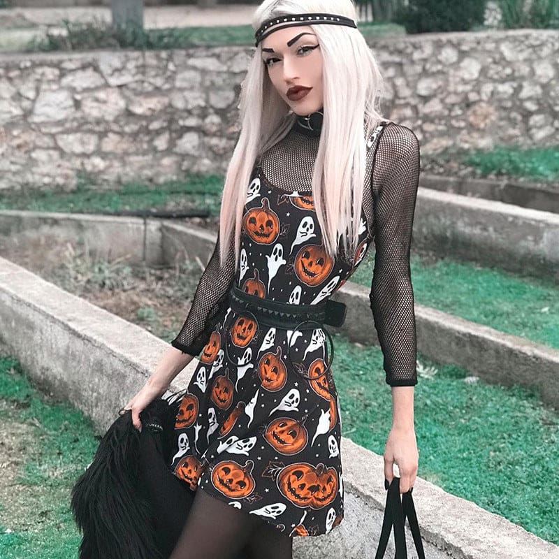 Angled outfit view of the black pumpkin-and-ghost skater dress beside stone steps, styled with black accessories and a sheer underlayer.
