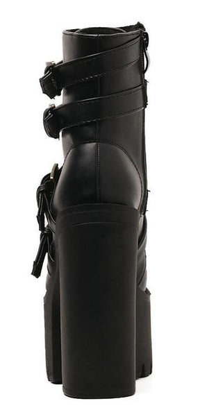 Rear view of a black ankle boot highlighting the tall heel, back seam and wrapping buckle straps.