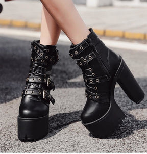 Black platform boots worn outdoors on pavement, showing the lace-up fronts and side zip against bare legs.
