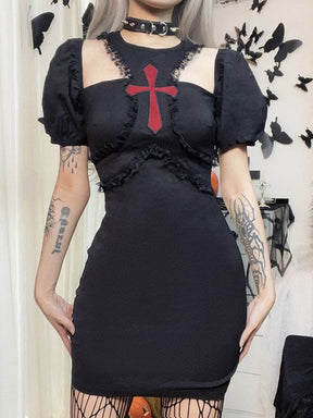 Straight front view of a model in the black cross dress, with hands resting at the hips below the lace-trimmed under-bust seams.