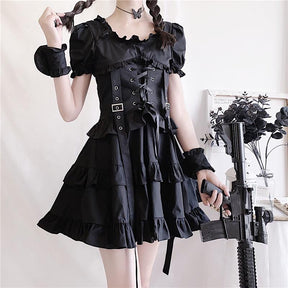 Black short-sleeved ruffle dress shown from the front with a laced corset harness, wide skirt and a costume prop held to one side.