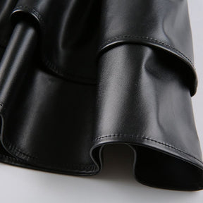 Close view of the glossy black faux leather folds in a ruffle tier, showing the surface shine and stitched edge.