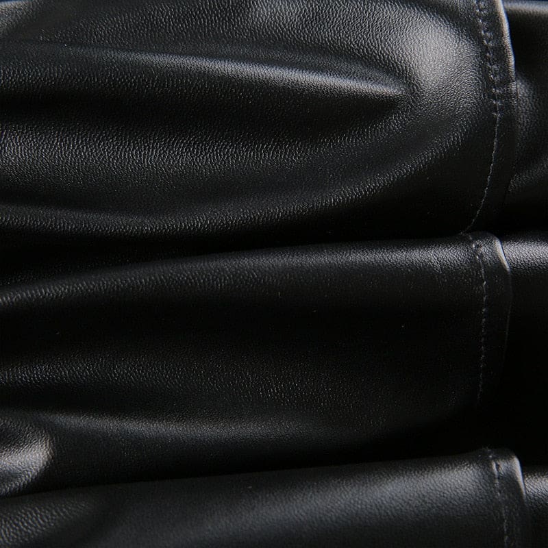 Macro view of the textured black faux leather used in the ruffle skirt, with reflected light across the surface.