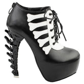 Black platform ankle boot in an outer-side view, showing pale bone-shaped trim, front laces and a sculpted black spine heel.