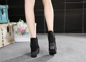Rear view of black platform wedge sneakers worn indoors, showing the raised heel profile and back seams.