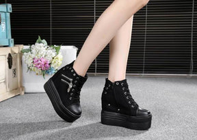 Black platform wedge sneakers shown from the inner sides in a seated pose, with one foot slightly lifted.