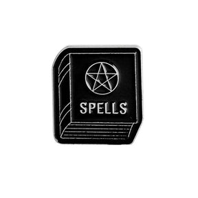 Black rectangular spellbook enamel pin with silver-tone cover lines, the word Spells and a central pentagram.