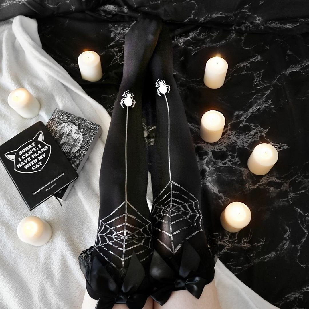 Black over-the-knee stockings with contrasting spiderweb patterns, dangling spider motifs, and black bows at the tops