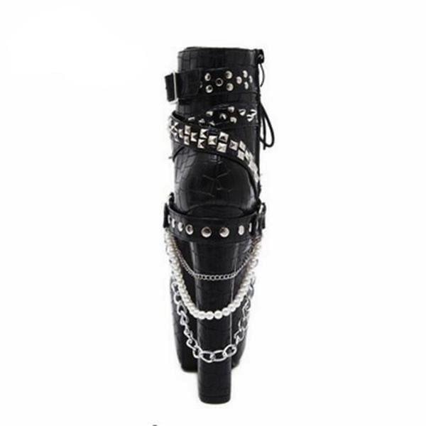Rear view of a black reptile-textured platform ankle boot, showing straps wrapped around the ankle and layered chains and pearl-like beads draped beside the heel.
